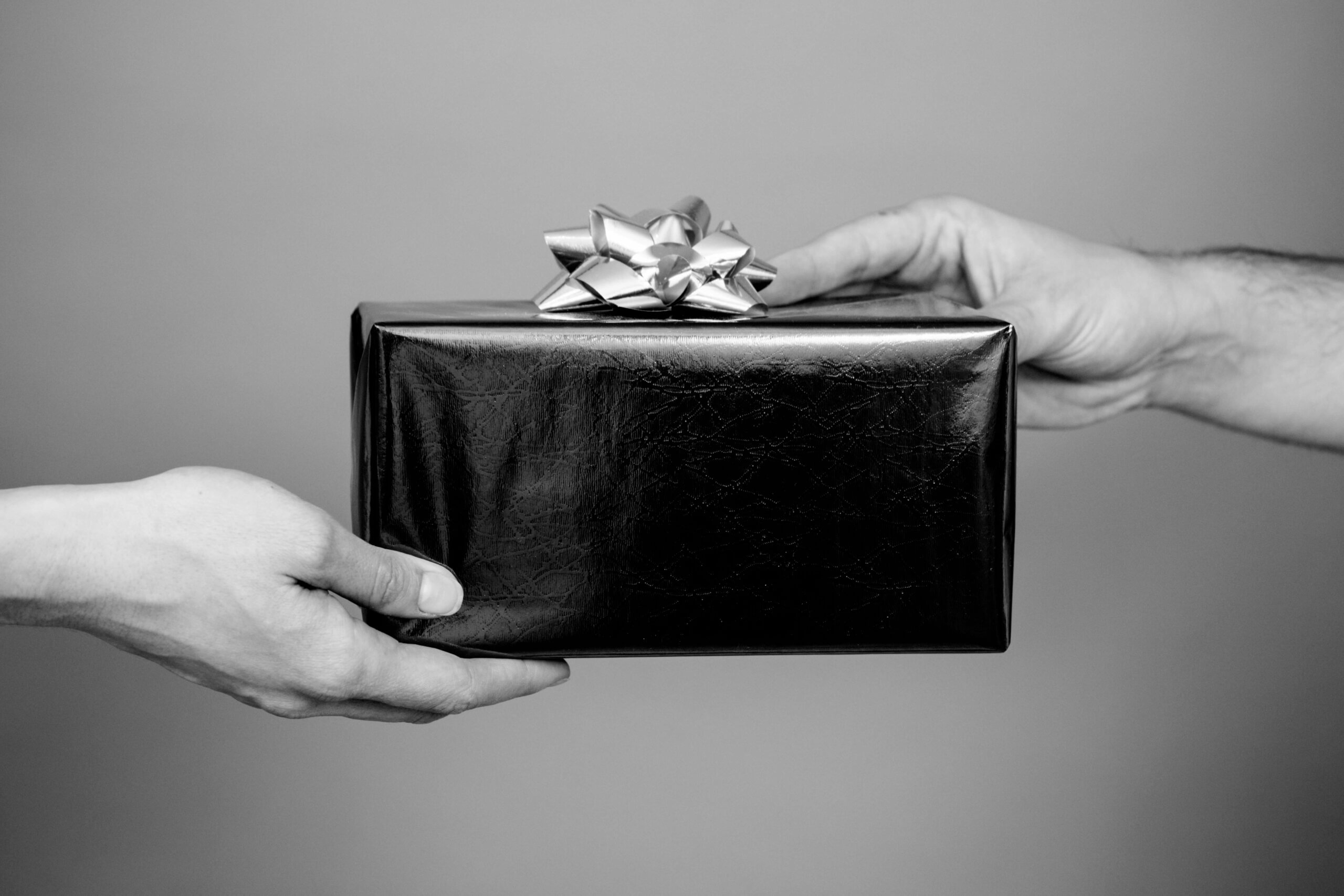 Two hands exchange a wrapped gift