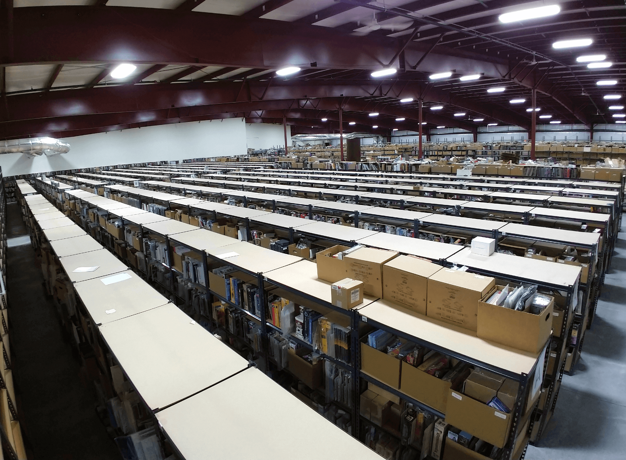 Noble Knight Games - meet our warehouse An aerial view from the inside of a large warehouse extending off into the distance with many rows of boxed games on storage shelves